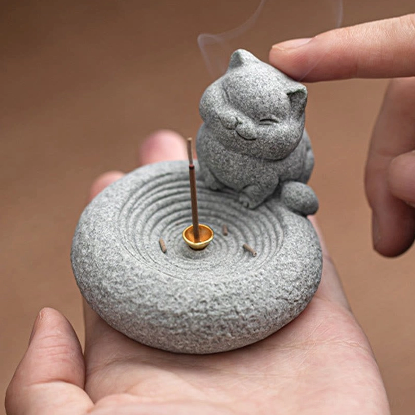 Handcrafted cat incense burner held in human hand with lit incense and smoke
