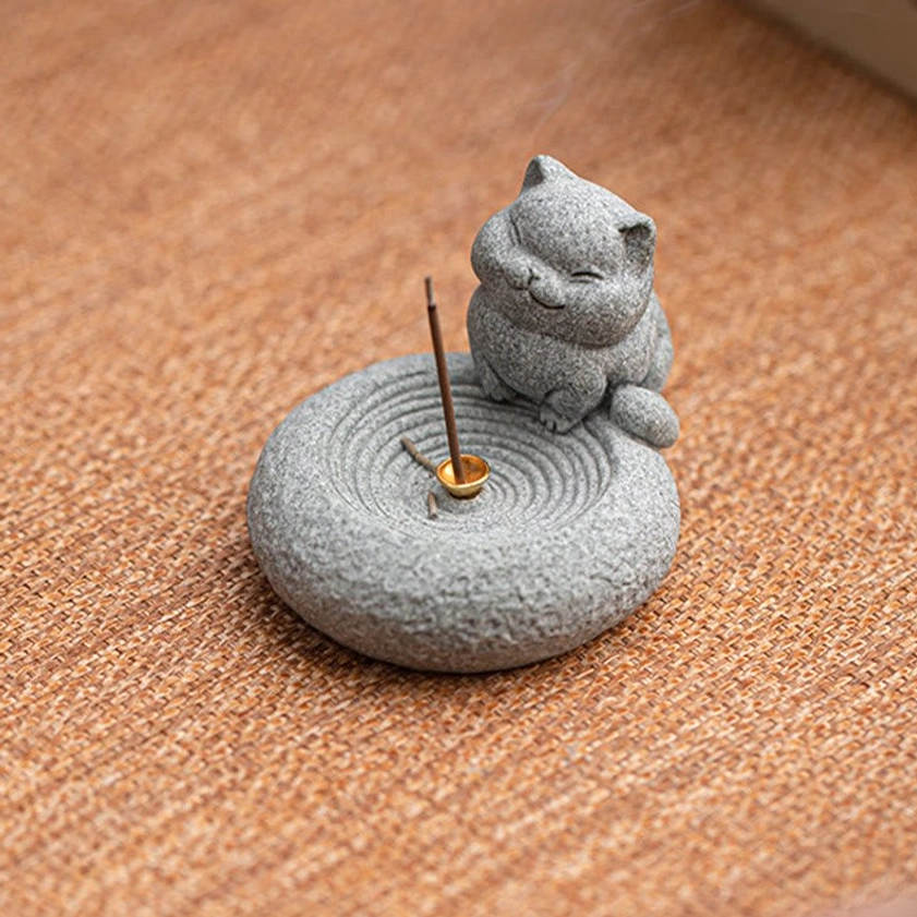Overhead view of smiling cat incense burner on burlap with golden metal socket