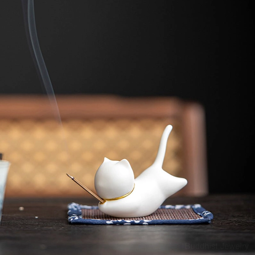 Cat ceramic incense holder front low angle view with gentle incense smoke rising, soft studio lighting, warm indoor ambient setting
