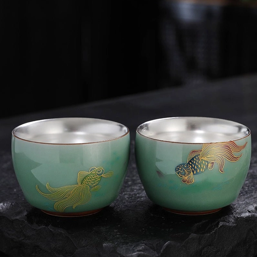 Celadon Buddhist tea cup with delicate hand-painted floral motif and silver-lined interior for meditation and mindfulness