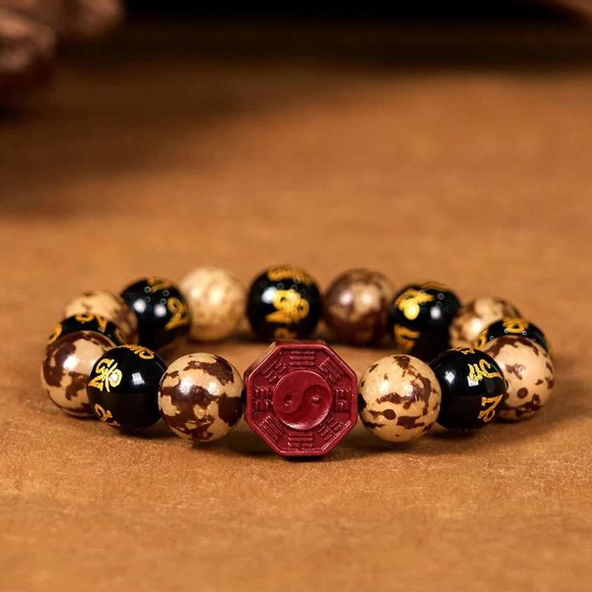 Centered Bagua bracelet overhead flat lay with red cinnabar center bead and mixed Bodhi seed beads on textured brown backdrop