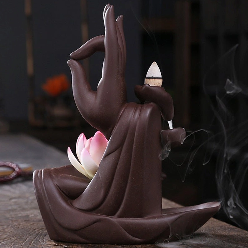 Rear three-quarter view of handcrafted ceramic buddhist incense burner with lit cone incense and wispy aromatic smoke