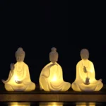 Ceramic Buddha LED decoration set with multiple handcrafted bodhisattva statues showing warm LED light on dark wooden display table