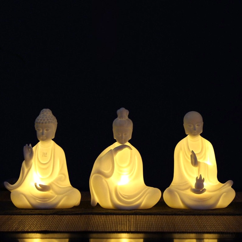 Ceramic Buddha LED decoration set with multiple handcrafted bodhisattva statues showing warm LED light on dark wooden display table