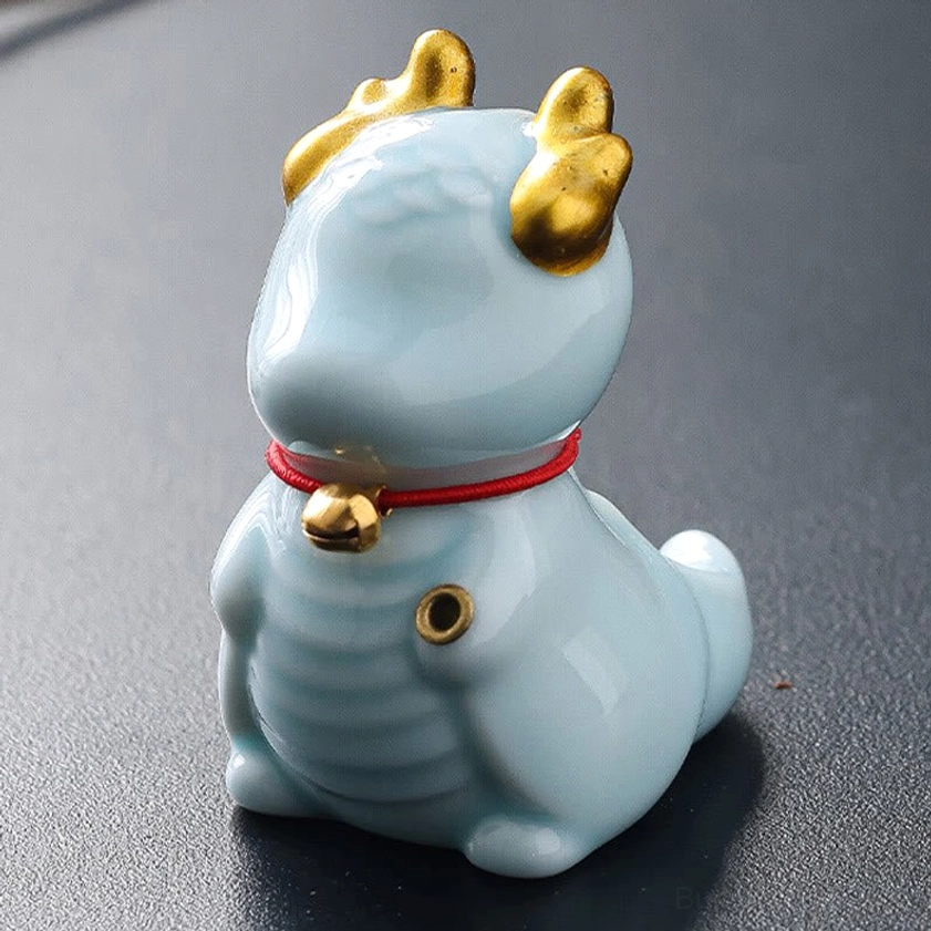 Light blue ceramic dragon incense holder front three-quarter view with shiny golden accents and red bell