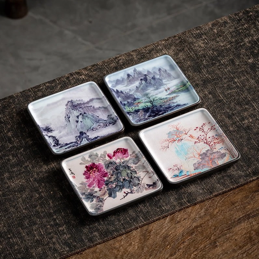 Set of four artistic ceramic incense burner trays featuring landscape and floral Buddhist designs in flat lay overhead view