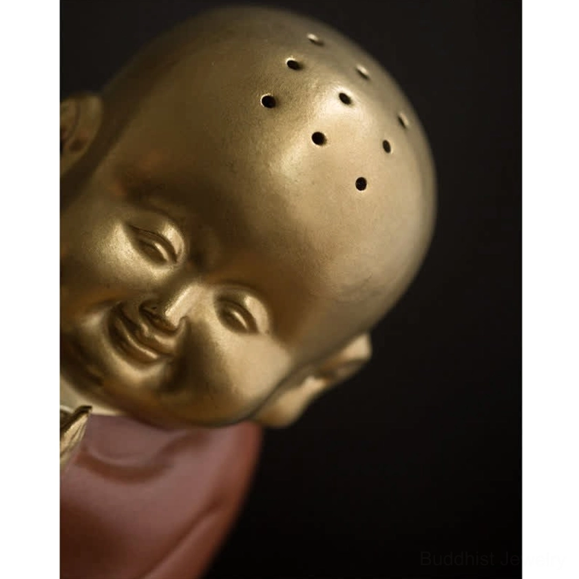 Ceramic incense burner extreme close-up head view showing multiple small perforations and subtle smiling face expression