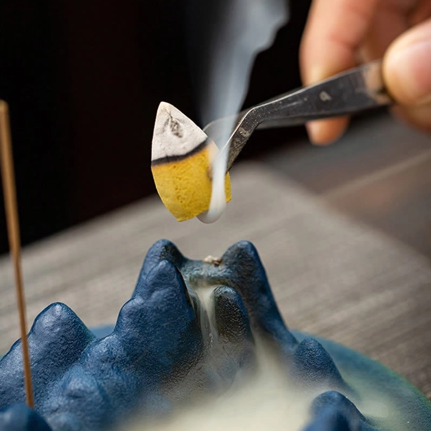 How to use Buddhist incense burner - demonstration of placing incense cone on burner peak using tweezers with active backflow smoke