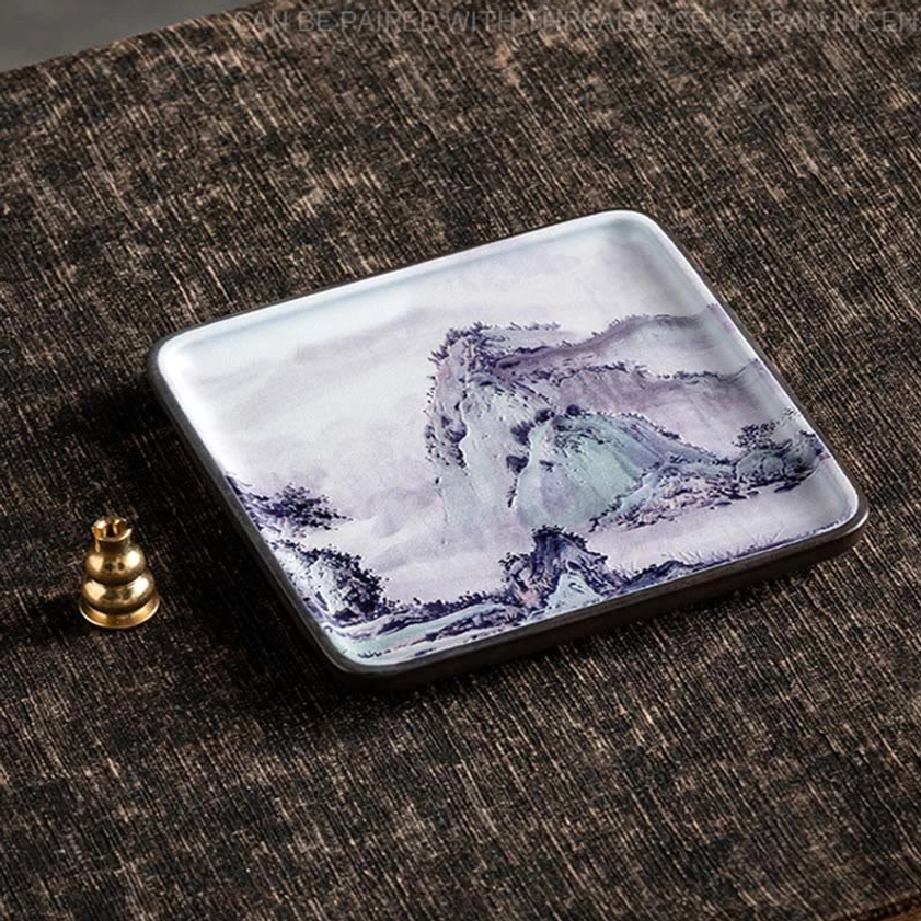 Handcrafted ceramic incense burner with landscape print design and brass incense holder on neutral linen mat