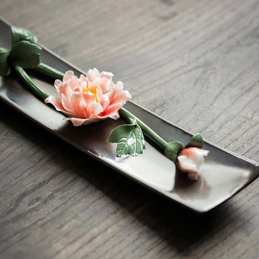 Ceramic incense holder with pink peony and bud detail, side close-up view on dark ceramic tray