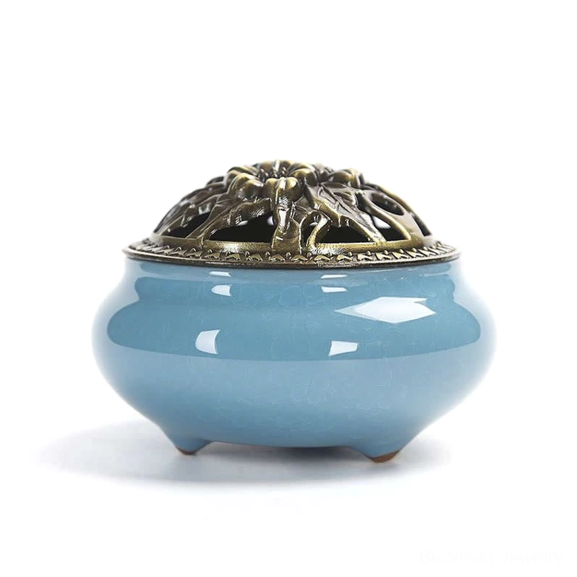 Sky-blue ceramic incense burner with bronze carved hollow lid and three-footed base, front view on white background