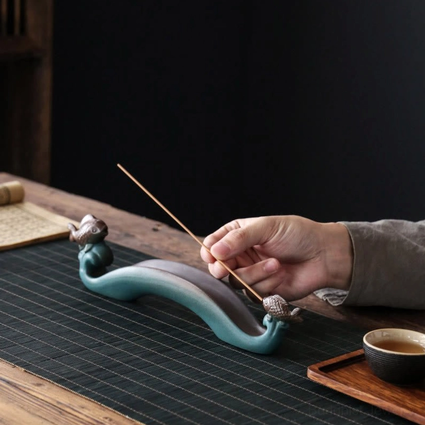 Double Koi Fish incense holder side close-up view with hand placing incense stick