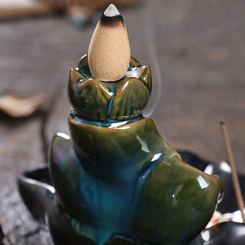 Teal-green ceramic lotus incense burner with cone incense and smoke trail