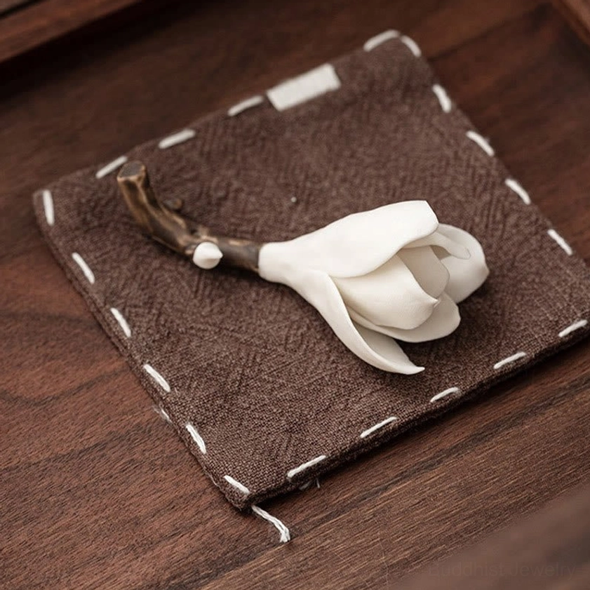 Top-down flat lay of ceramic magnolia incense holder placed on dark wooden table with stitched linen coaster showing handmade design