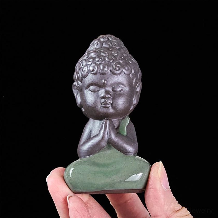 Ceramic meditation monk statue bottom view held by fingertips showing base