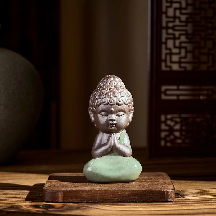Ceramic meditation monk statue in prayer pose displayed on wooden base with peaceful expression