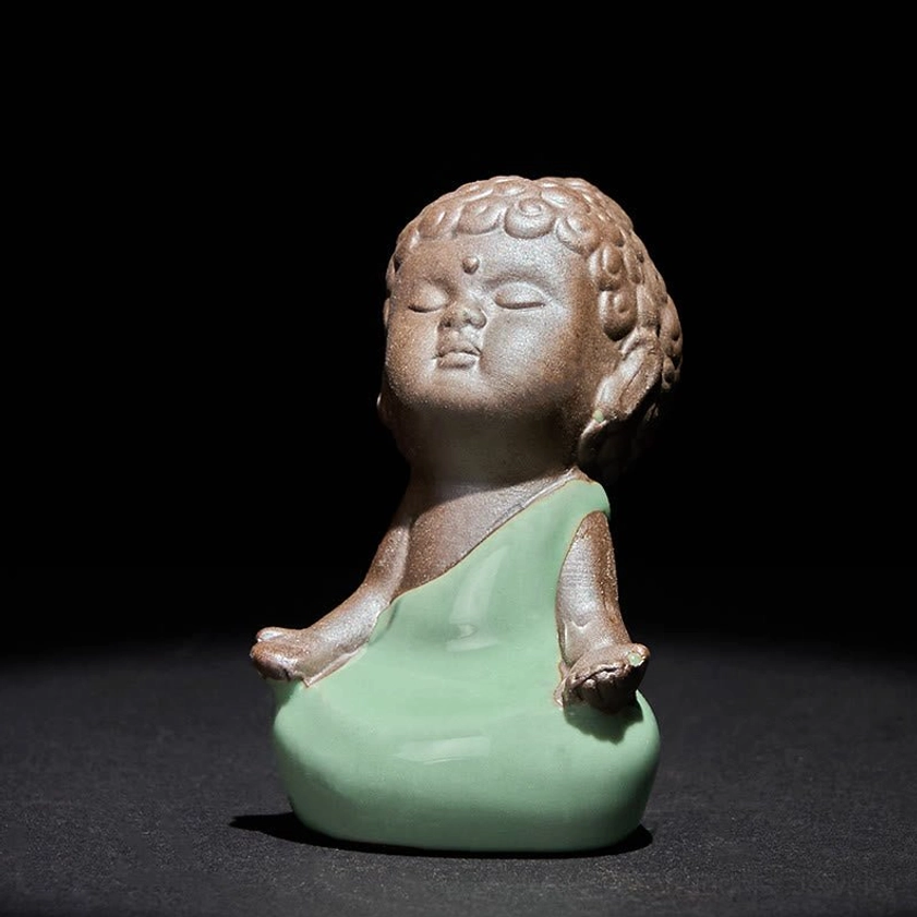 Handcrafted ceramic meditation monk statue displayed on wooden altar surface