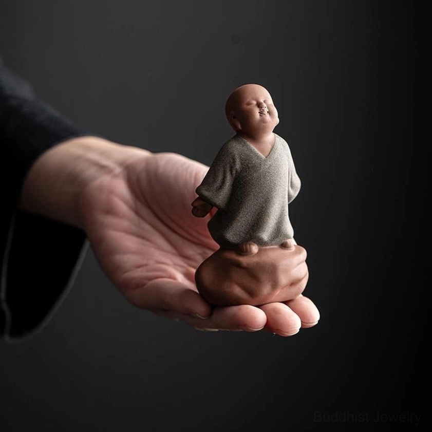 Grey ceramic monk statue held in human hand showing actual size and miniature scale detail