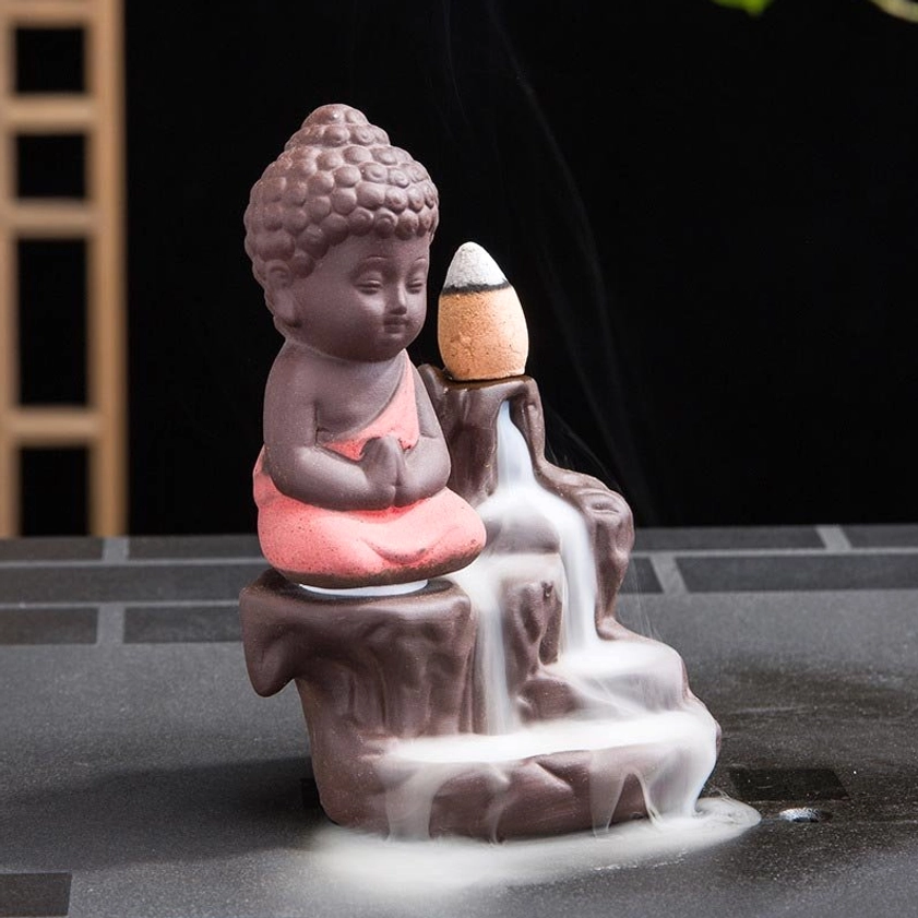 Three-quarter side view of ceramic monk incense burner showing cascading waterfall smoke effect and rock base