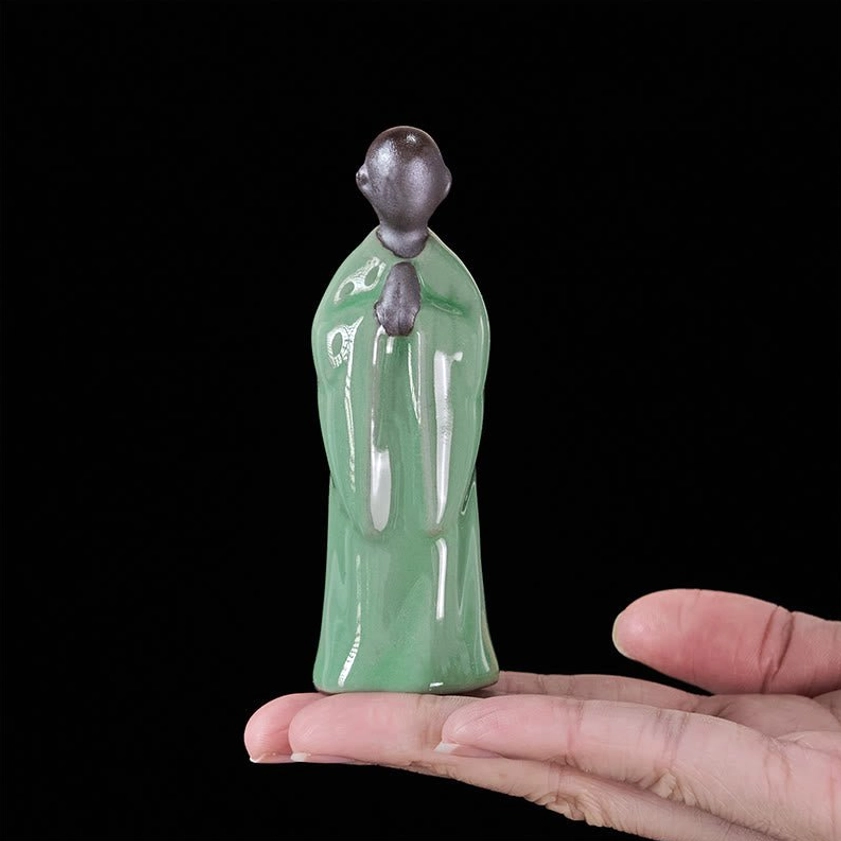 Close-up detail shot of handcrafted ceramic monk statue showing glazed surface and facial features
