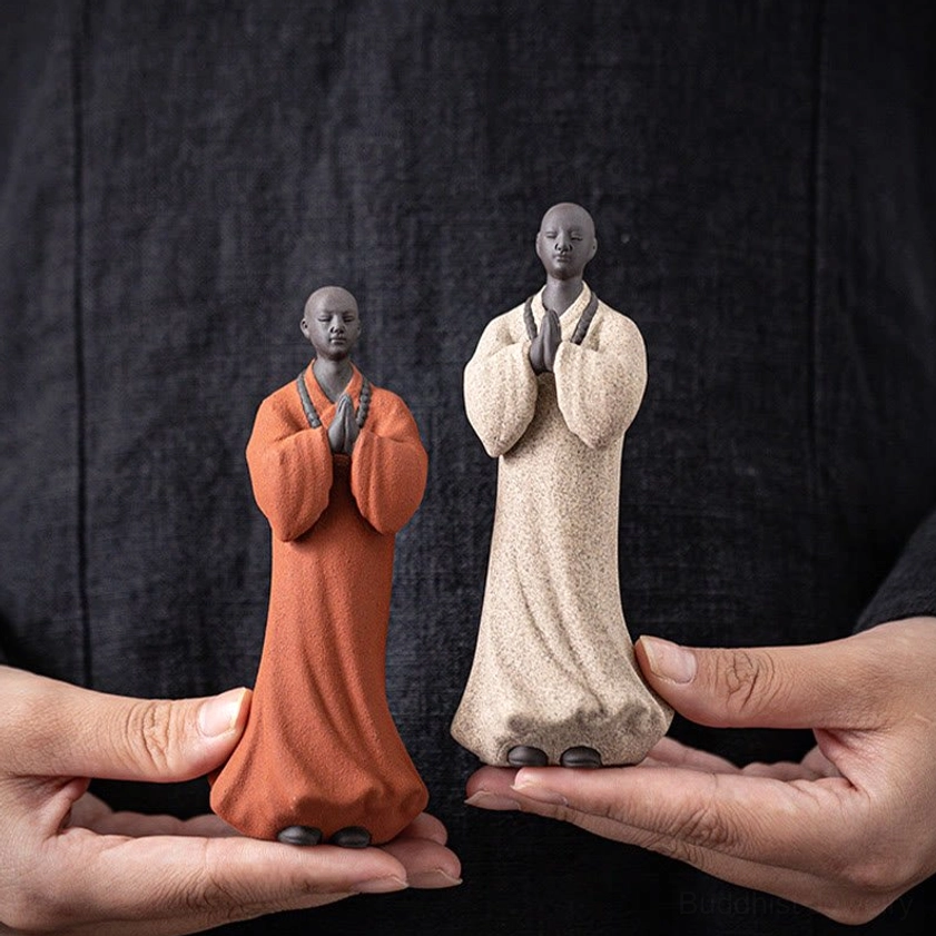 Portable handcrafted ceramic meditation monk statue held in hands showing compact size and matte texture