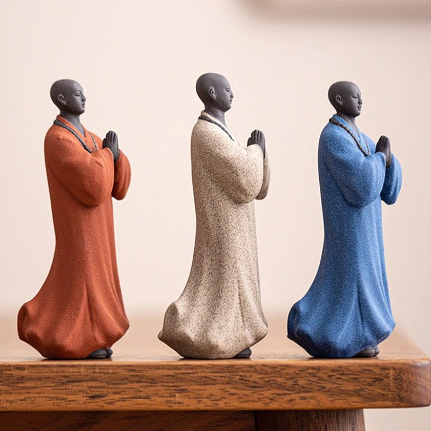 Side profile view of handcrafted ceramic meditation monk figurines showing detailed robe texture and prayer necklaces