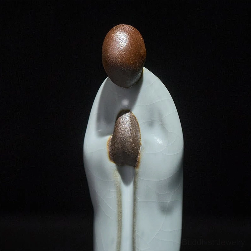 Side profile of handcrafted ceramic meditation monk figurine on wooden display base