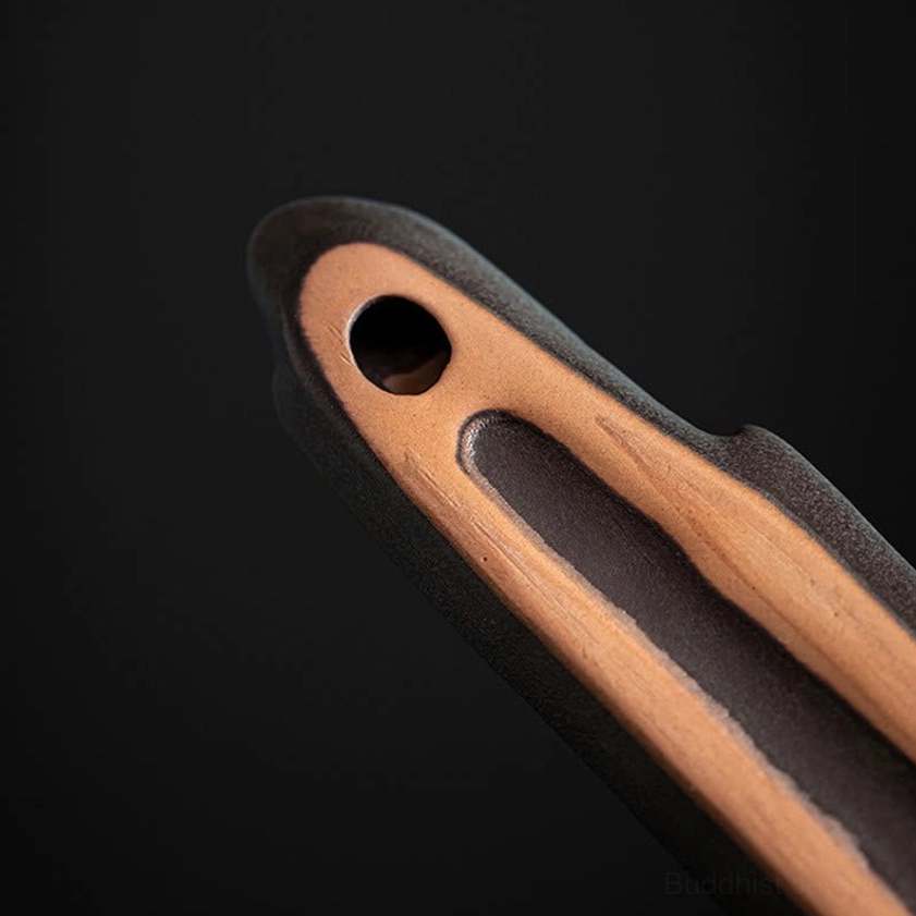 Close-up cross-section cutaway detail of ceramic incense burner showing dual-tone brown and black texture and internal stick-holding mechanism