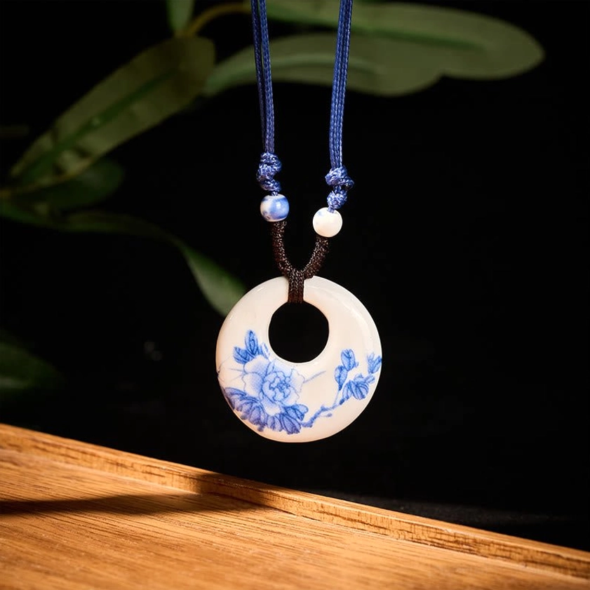 Blue and white ceramic pendant side hanging view showing small blue floral print design on dark background