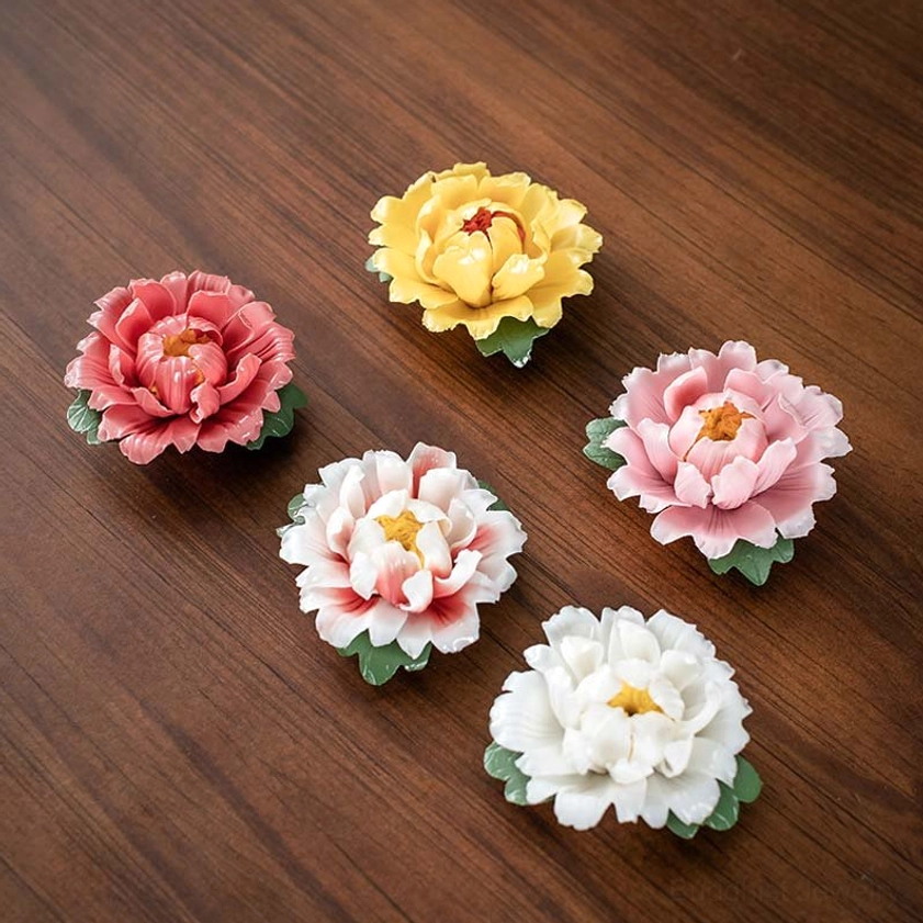 Multiple peony ceramic incense burners in different colors arranged on wooden table