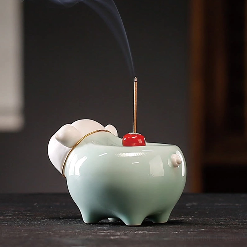 Rear view of ceramic pig incense burner on dark wooden table with curling incense smoke, red cherry on top