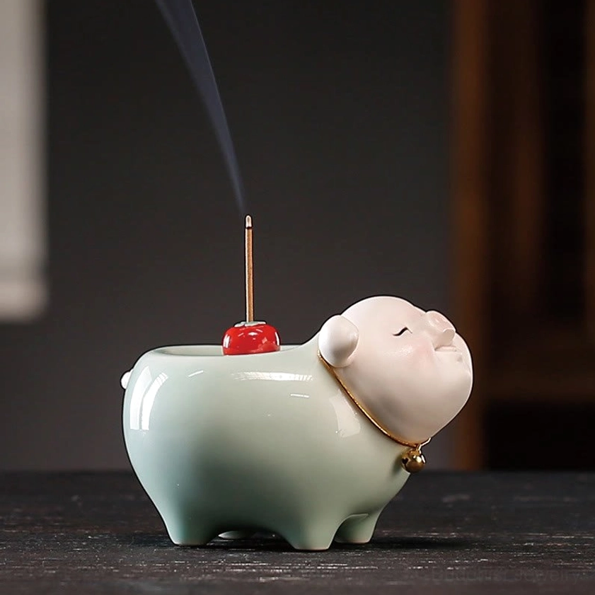 Side front view of ceramic pig incense burner with drifting incense smoke, showcasing celadon glaze texture and detail