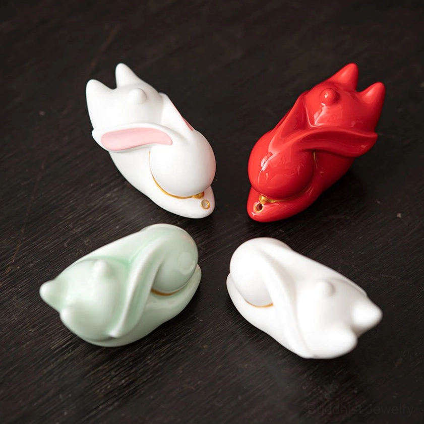 Four ceramic rabbit incense holders in white, red, and light green color options displayed top-down on dark wooden table