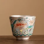 Handcrafted ceramic gongfu tea cup with fish and lotus motif, 45ml capacity, front view on wood table