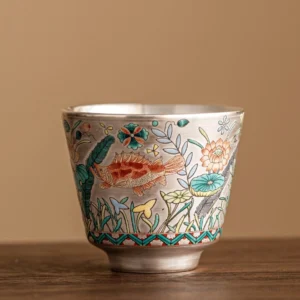 Handcrafted ceramic gongfu tea cup with fish and lotus motif, 45ml capacity, front view on wood table