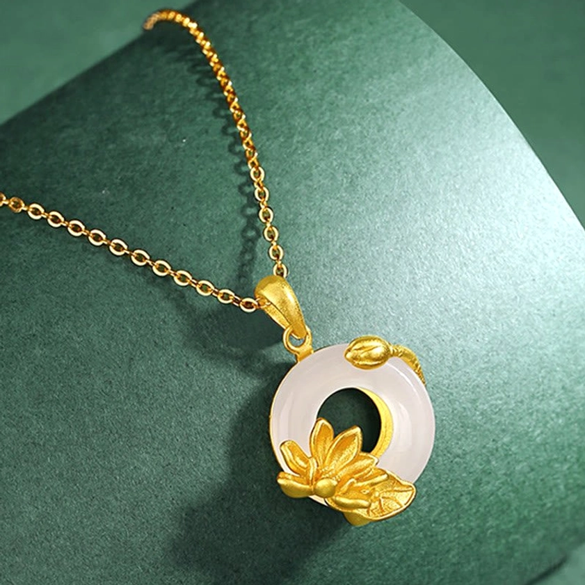 Buddhist necklace featuring white chalcedony peace buckle with delicate gold lotus and bud decoration on dark green surface