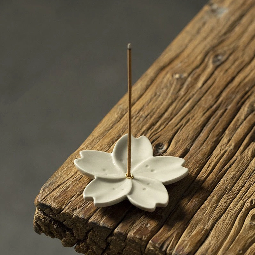 Cherry blossom shaped ceramic incense holder with notched petals and central metal incense pin