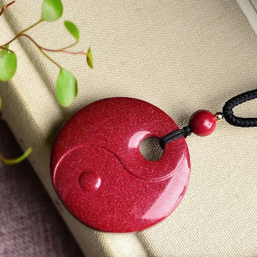 Chinese zodiac animal cinnabar Buddhist pendant necklace with carved zodiac sign on wine-red stone displayed on ceramic tabletop