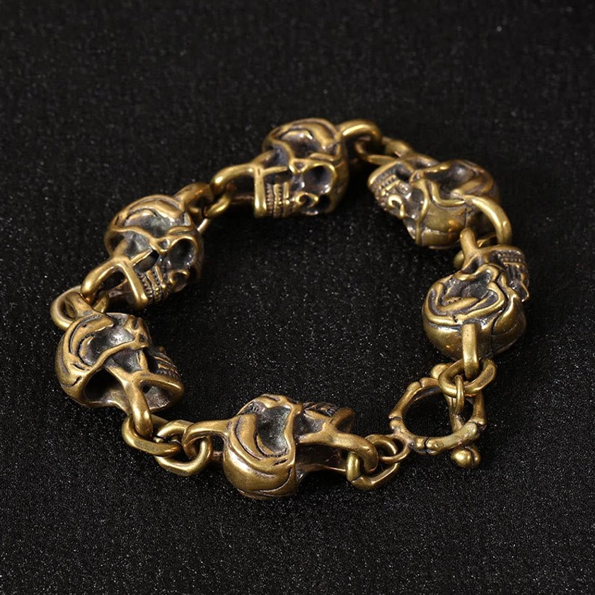 Thick brass skull chain bracelet circular flat lay with multiple intricately carved skull links - Buddhist protection amulet