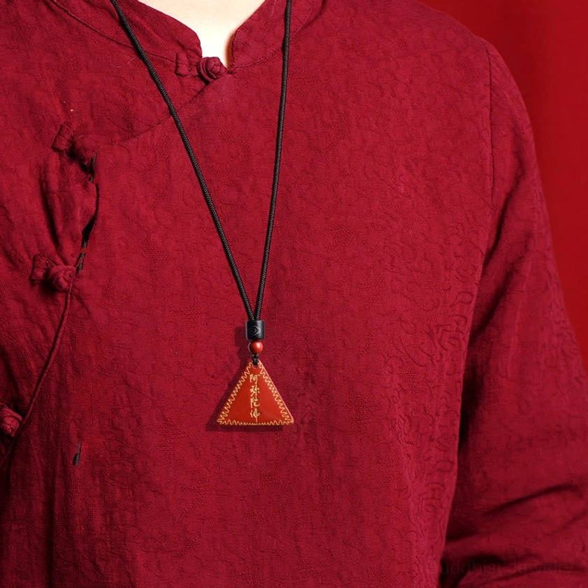 Amitabha Buddhist cinnabar pendant necklace worn on chest with thin black cord on maroon clothing
