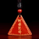 Red cinnabar Amitabha Buddhist pendant necklace with golden engraved characters and wavy gold border on dark background