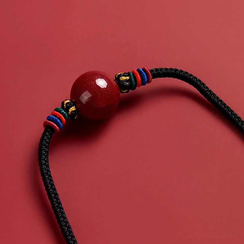Close-up side angle of glossy red cinnabar bead necklace - Buddhist pendant with mixed-color woven hardware detail