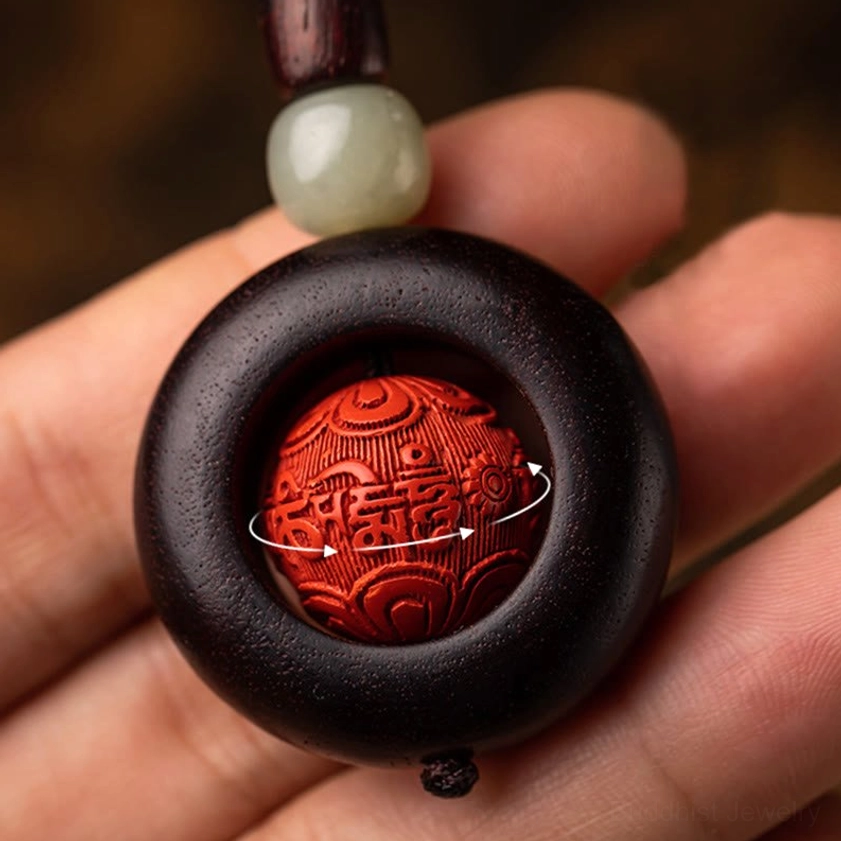 Close-up of rotating carved red cinnabar bead inside dark wood ring held in human palm, showing intricate craftsmanship