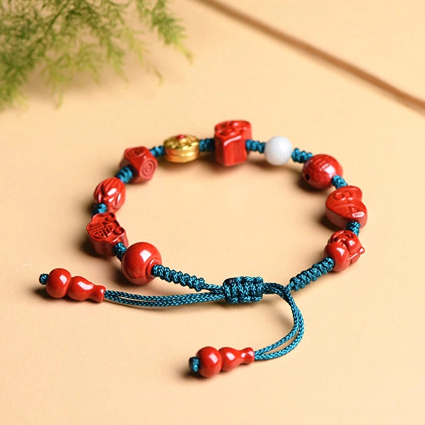 Overhead side view of red cinnabar Buddhist blessing bracelet displaying gourd-shaped tassel ends and assorted carved beads