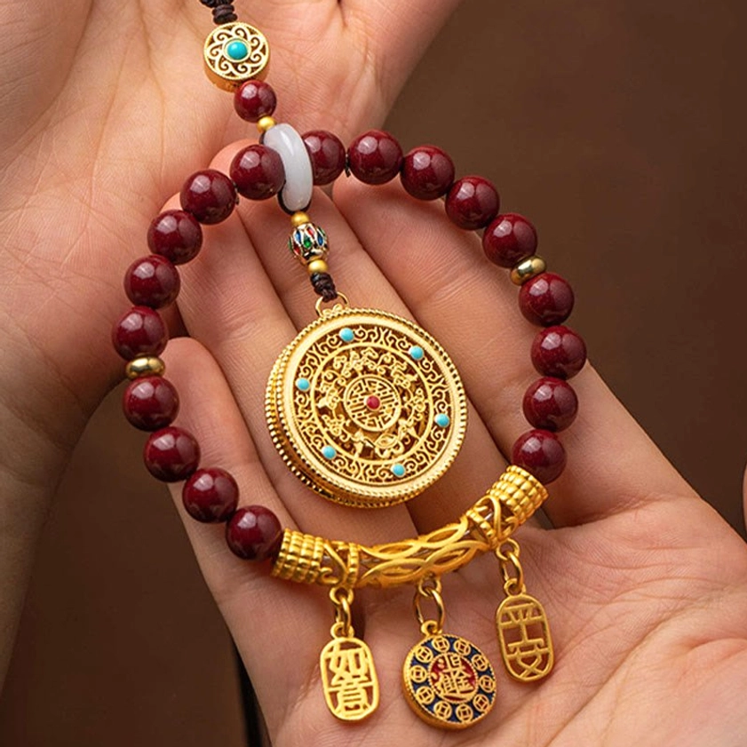 Handcrafted cinnabar ornament with enamel painted blessing charms and intricate gold filigree round pendant, front view detail