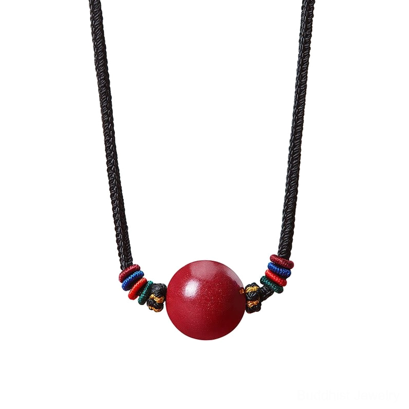 Front flat lay of red cinnabar blessing necklace - single large bead with colorful woven knots and simple black cord