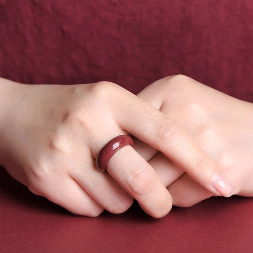 Hand model wearing polished cinnabar Buddhist ring on finger demonstrating comfortable fit and natural wearability