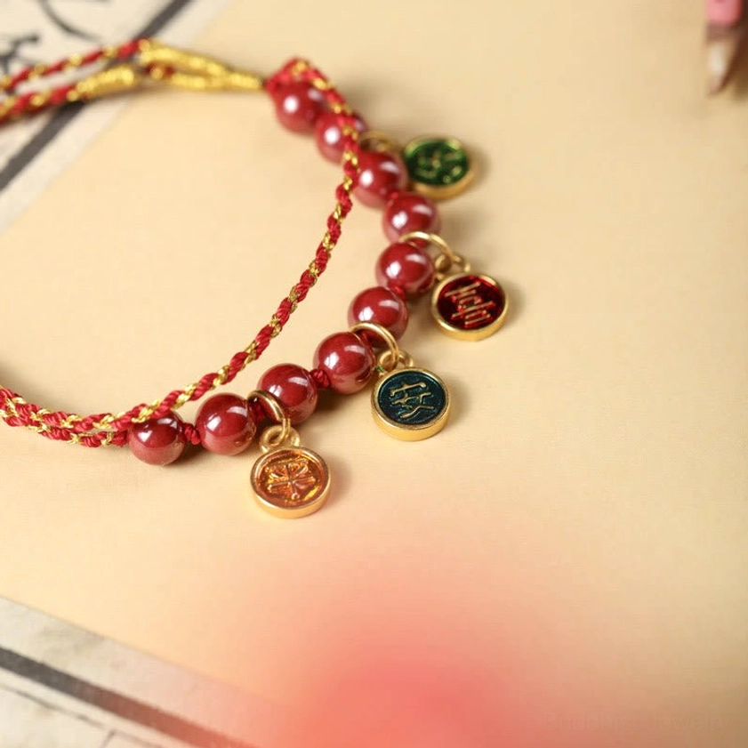 Close-up of cinnabar red string bracelet showing woven rope texture, beads and copper pendants in detail