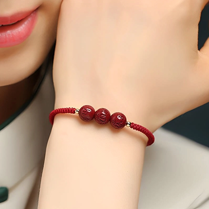 Adjustable cinnabar Buddhist bracelet displayed on wrist showing metal spacer beads and hand-braided red rope construction detail
