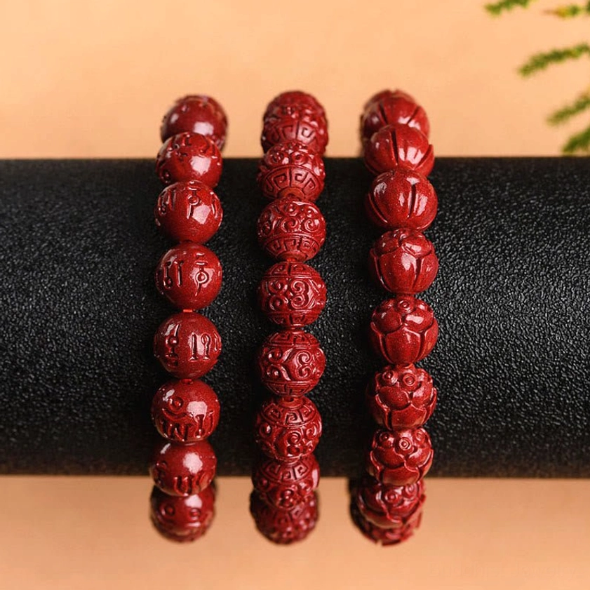 Handmade natural cinnabar prayer bracelet worn on wrist showing comfortable elastic fit and carved bead details in daily wear